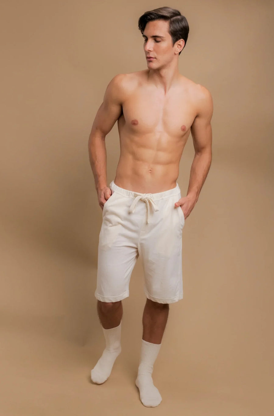 Man wearing allergy-friendly organic cotton shorts and socks, beige background