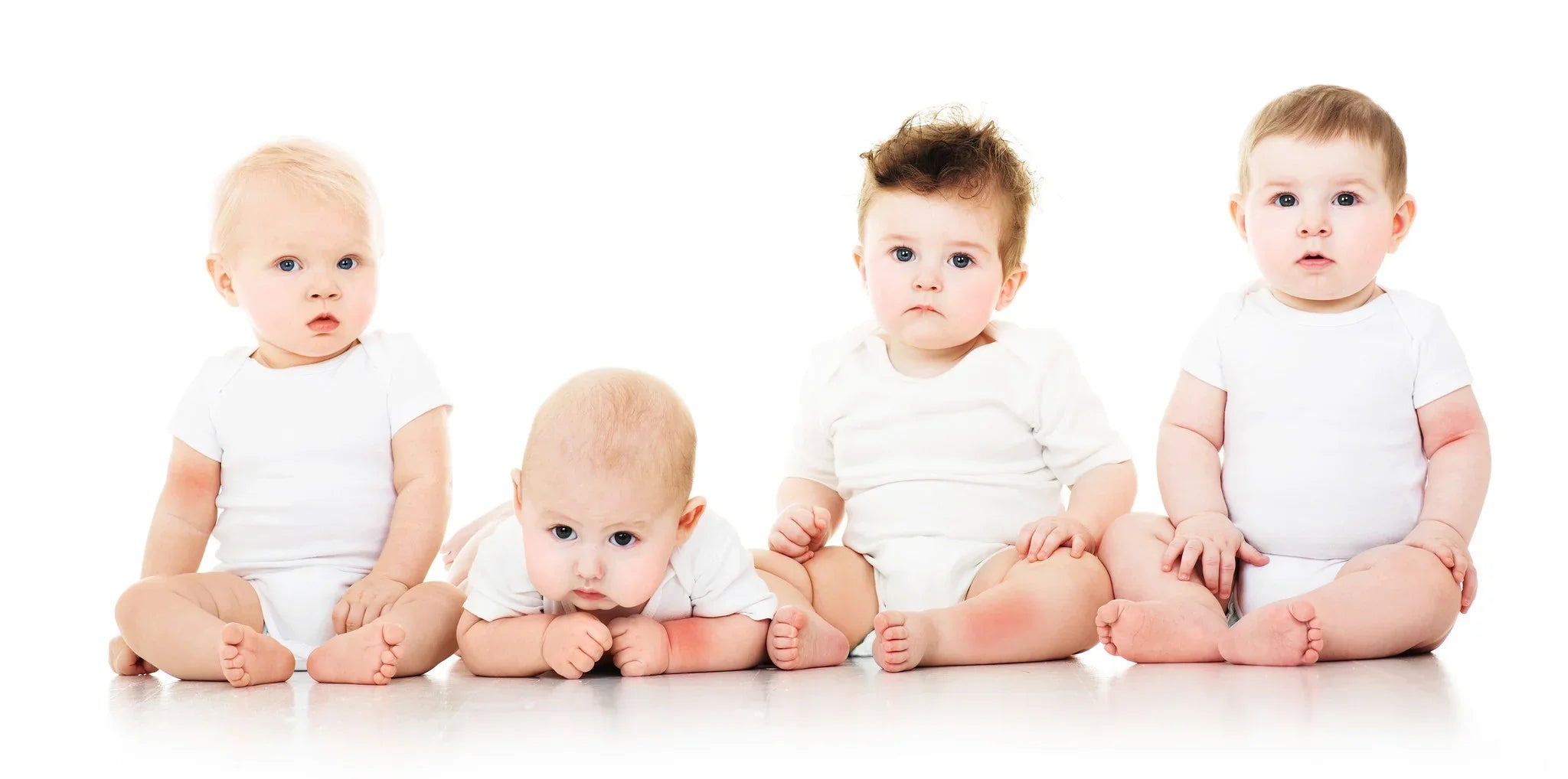 Four babies in white organic cotton bodysuits sitting on a white background