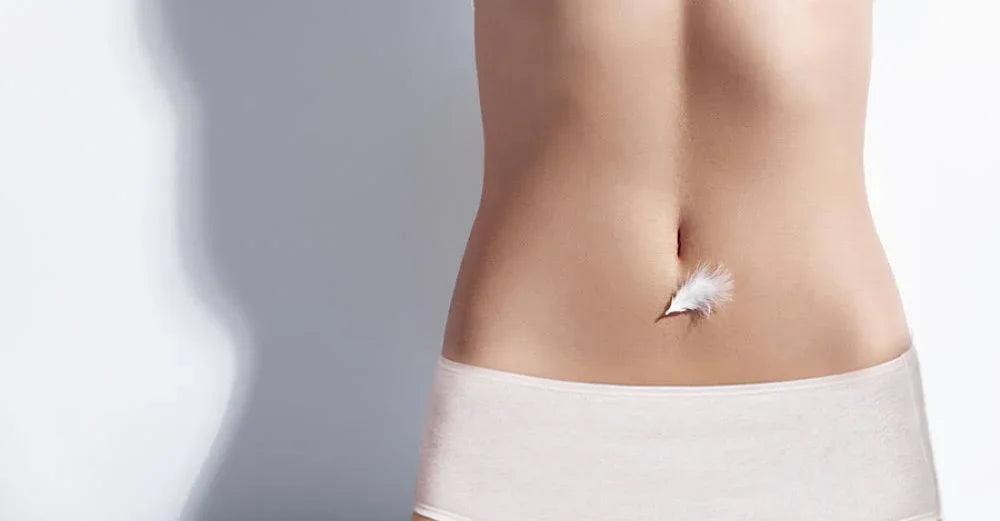 Woman wearing beige organic cotton underwear with a white feather on her stomach, symbolizing softness for sensitive skin