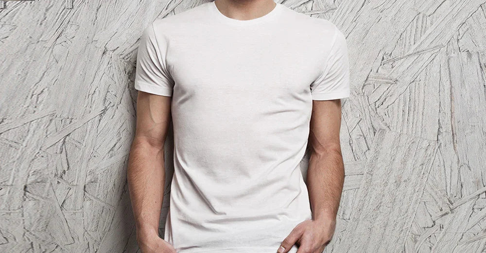 Man wearing plain white organic cotton t-shirt against textured wall, allergy-friendly clothing