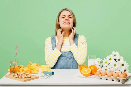 Woman scratching neck, showing signs of food allergy, surrounded by eggs, nuts, and citrus fruits.