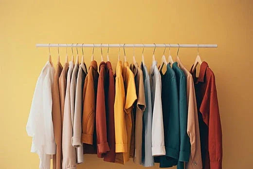 Assorted organic cotton shirts and tops in neutral and vibrant colors hanging on a rack