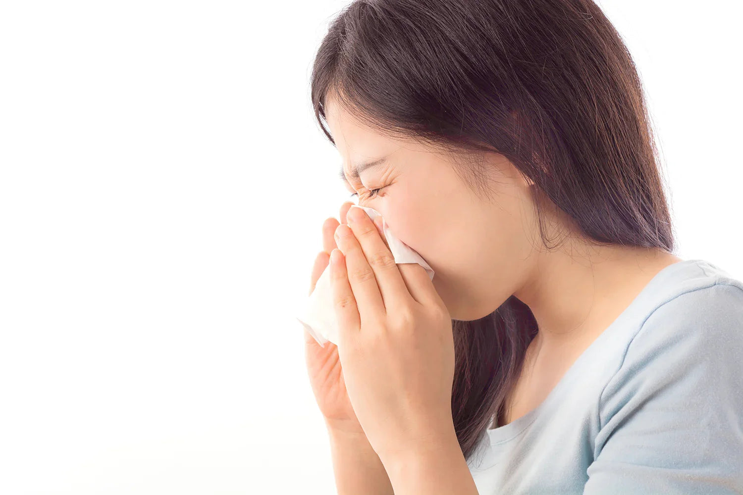 Woman sneezing into tissue, illustrating sensitivities for allergy-free hypoallergenic apparel
