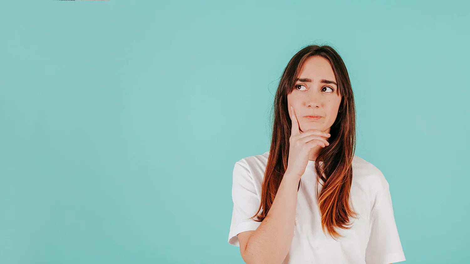 Woman in white allergy-free Cottonique shirt thinking, with blue background