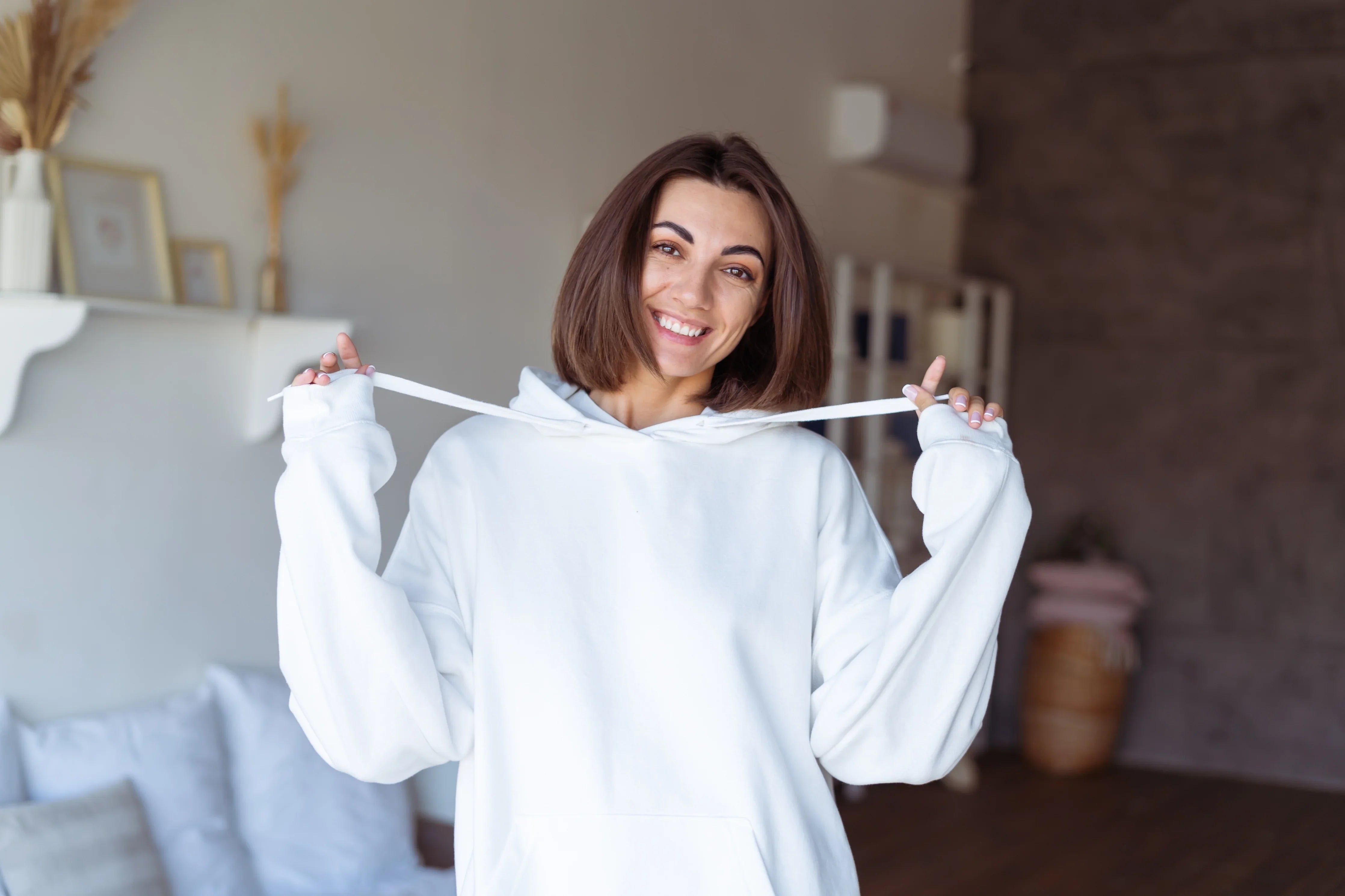 Smiling woman in a cozy white organic cotton hoodie at home