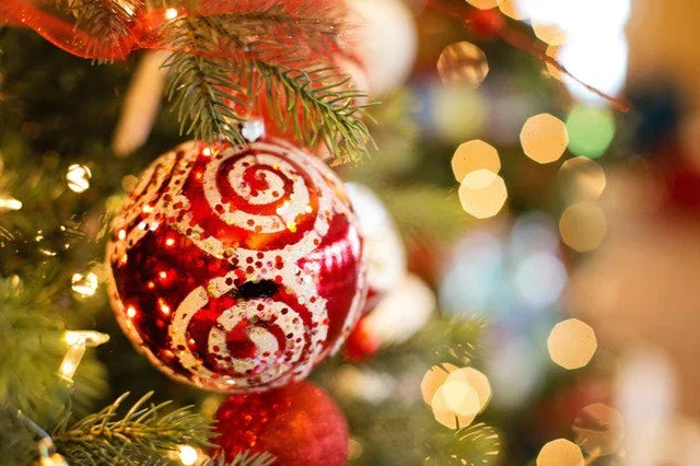 Red and white Christmas ornament hanging on decorated Christmas tree with warm lights