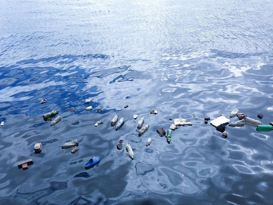 Plastic bottles and debris floating on polluted water surface, highlighting environmental issues.