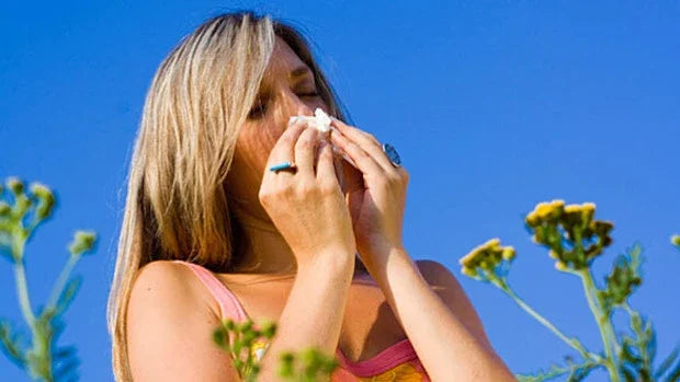 Woman outdoors sneezing near flowers, seasonal allergies, sensitive skin, organic lifestyle