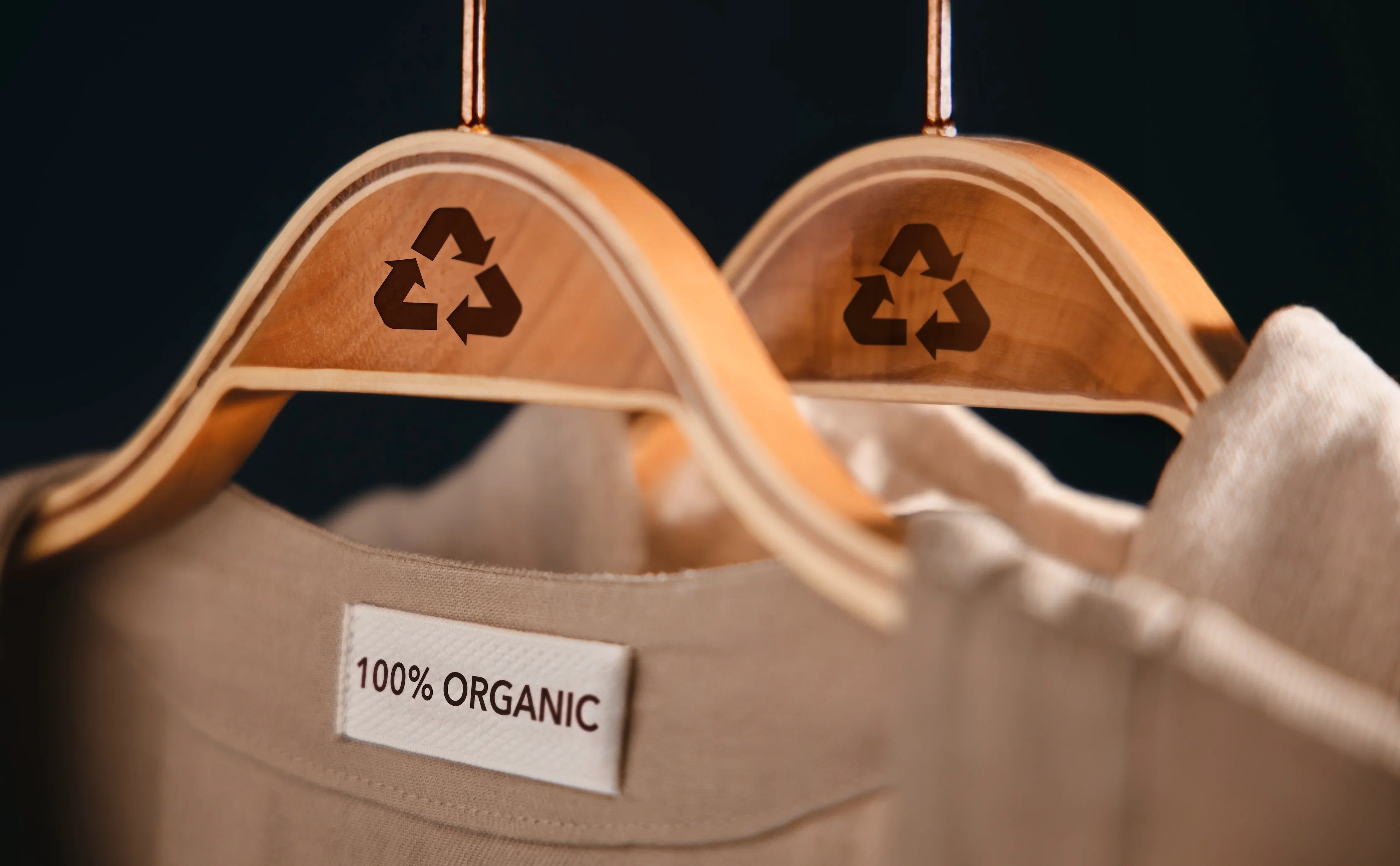 100% organic cotton clothing on wooden hangers with recycle symbols, eco-friendly apparel
