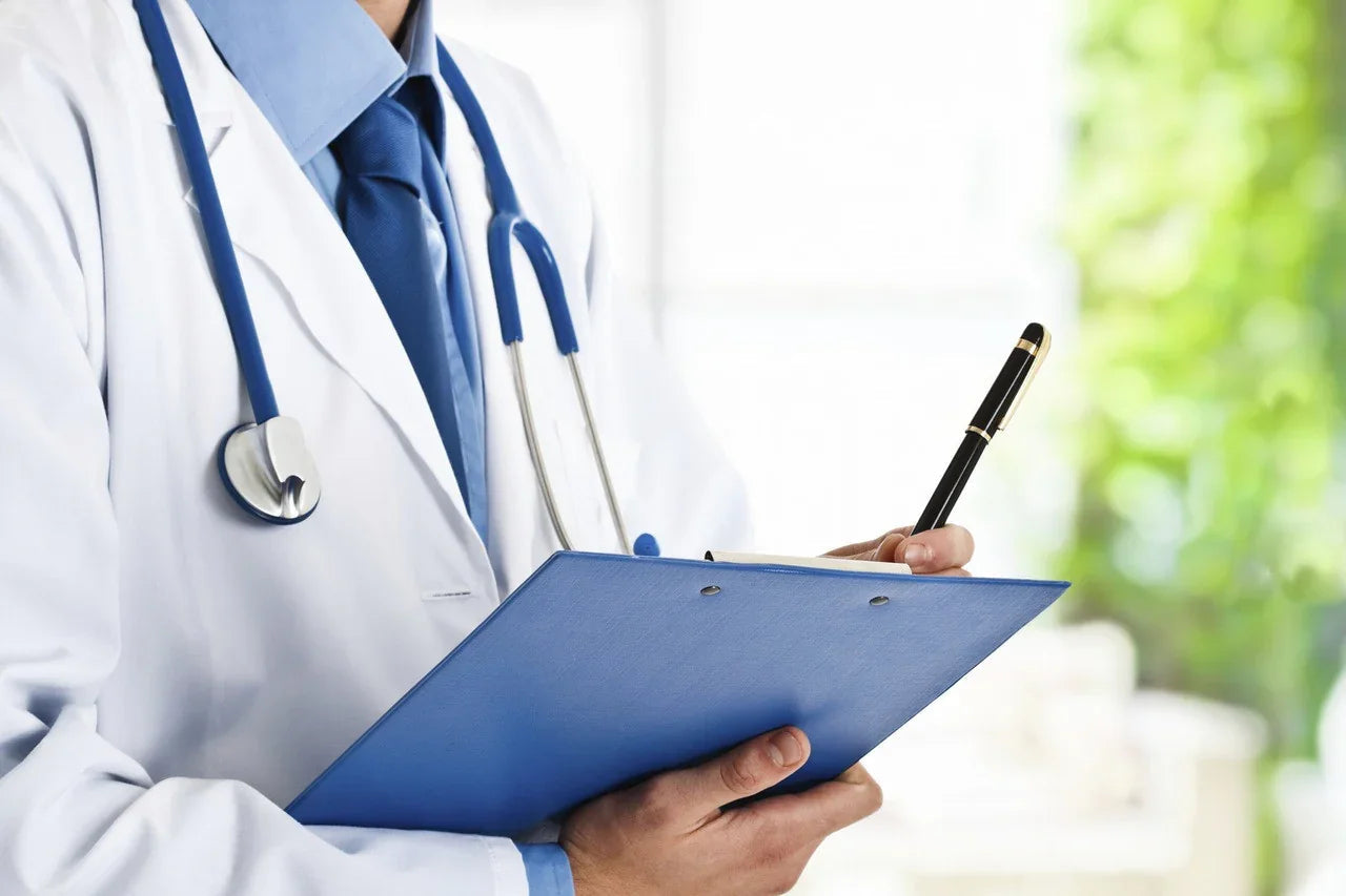 Doctor in white coat with stethoscope writing on clipboard in a bright clinic
