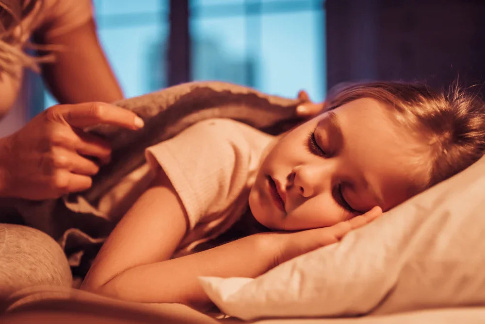 Child sleeping peacefully in bed with soft organic cotton bedding, gentle evening light.