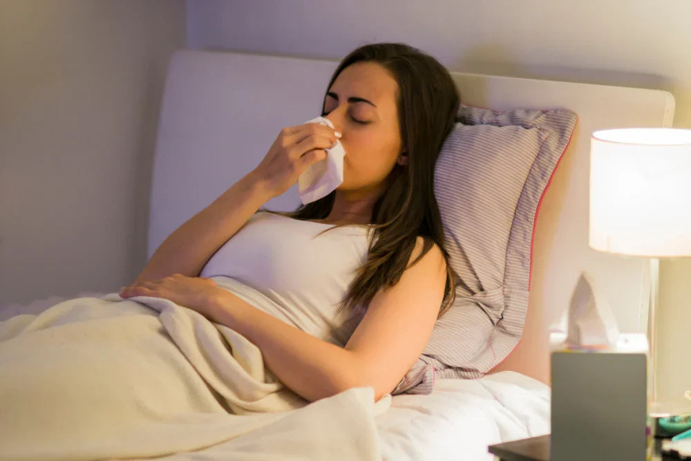 Woman in bed with tissue, allergy symptoms, organic cotton bedding, sensitive skin comfort