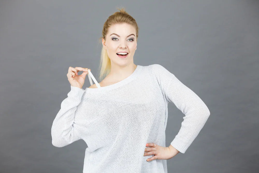Woman in soft knit sweater showing allergy-friendly cotton shoulder strap, grey background