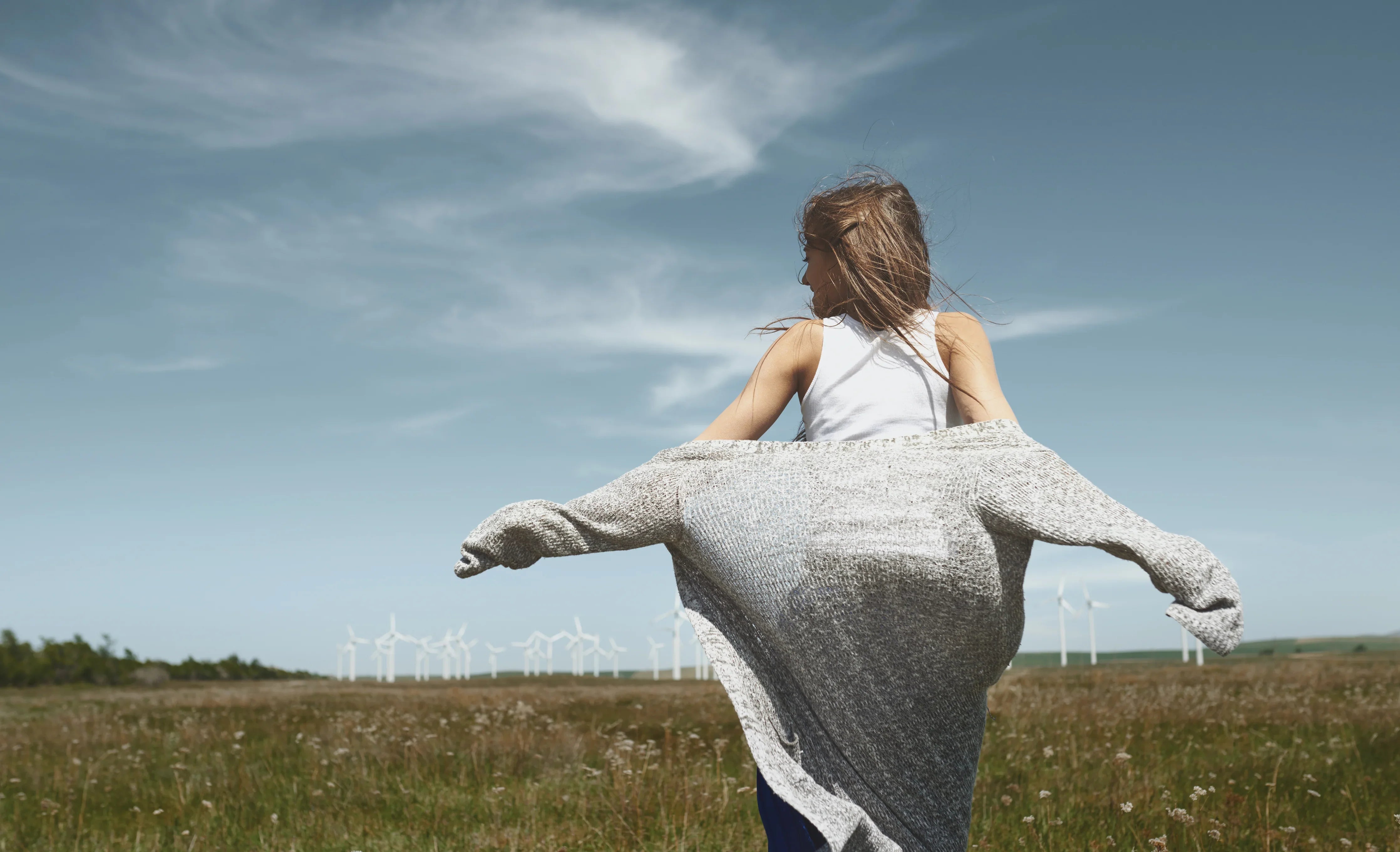 Woman in organic cotton clothing enjoying nature in a field with wind turbines