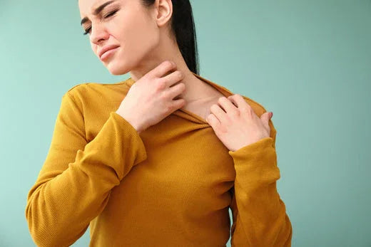Woman scratching neck in mustard top, showing sensitive skin irritation