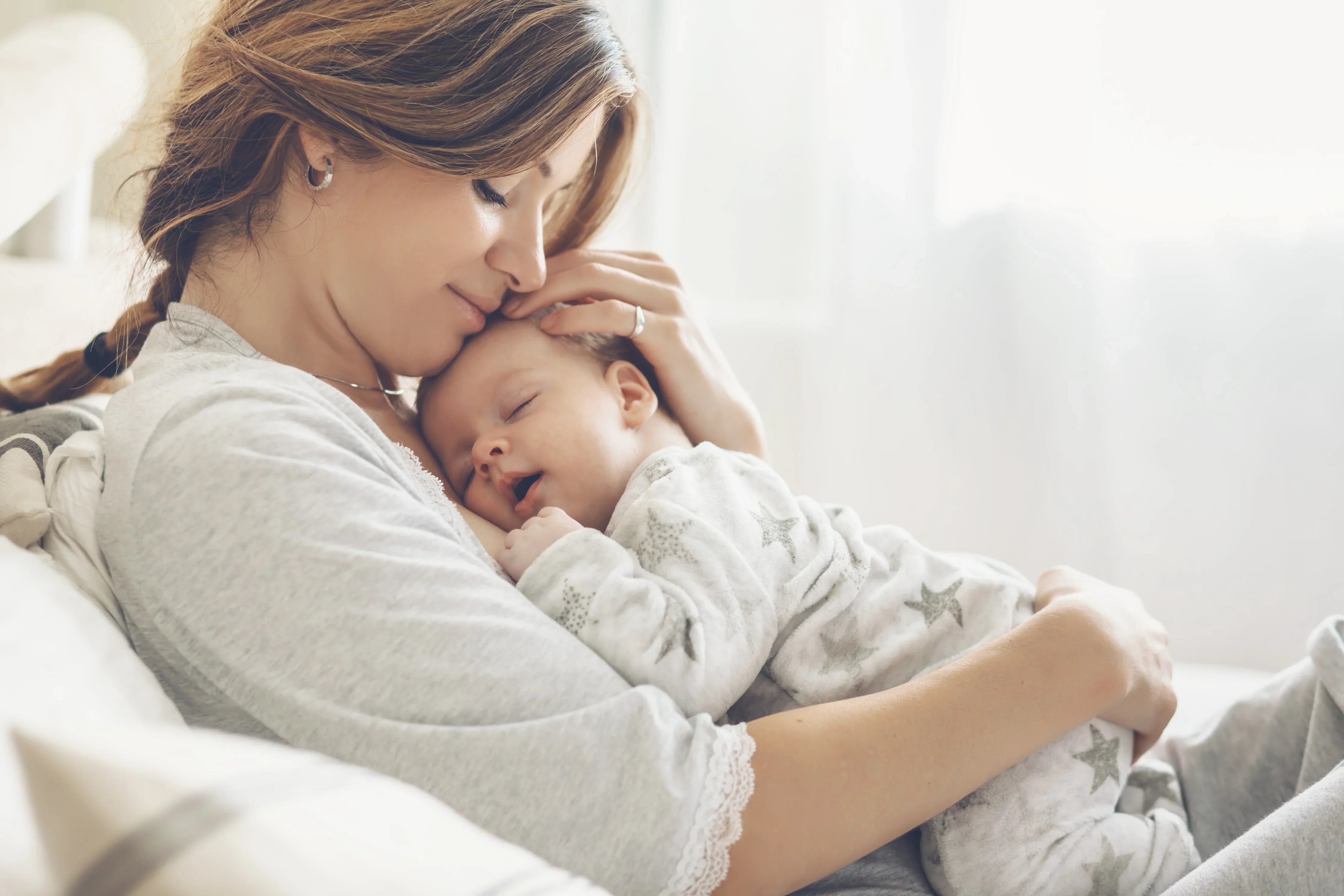 Mother cuddling baby in soft organic cotton clothing for sensitive skin