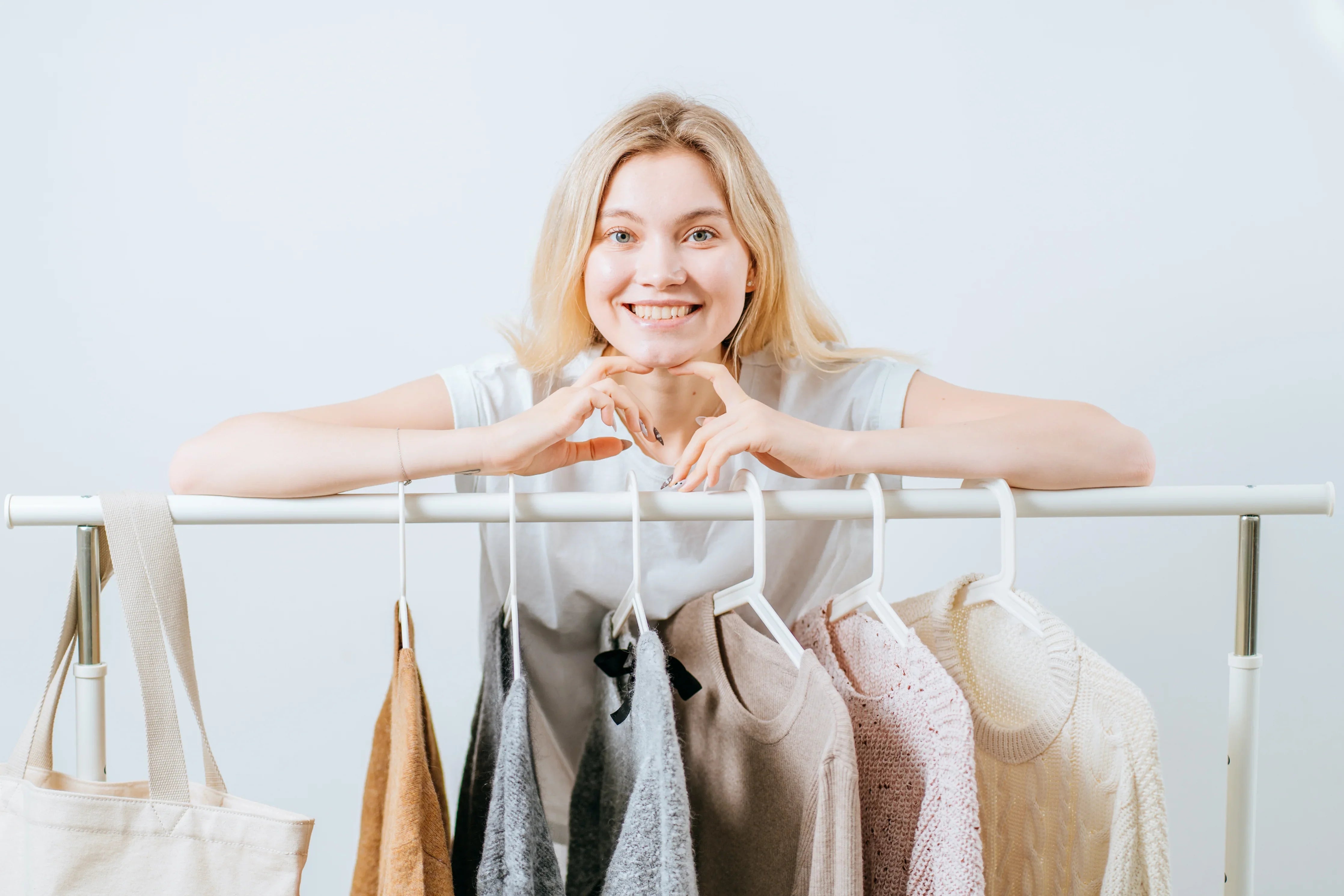 Smiling woman with sensitive skin standing behind rack of organic cotton clothing