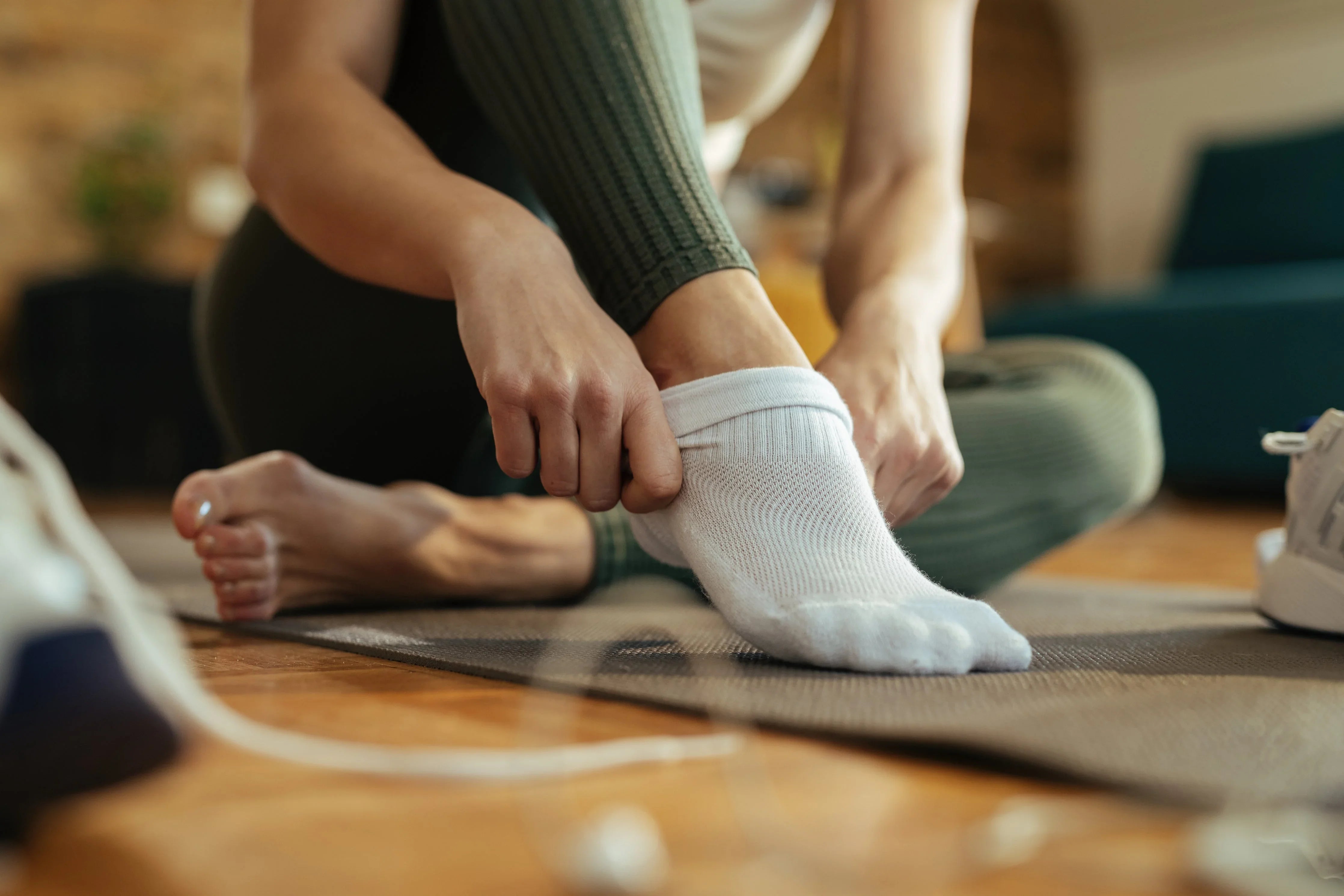 Person putting on white hypoallergenic cotton socks, allergy-free apparel indoors