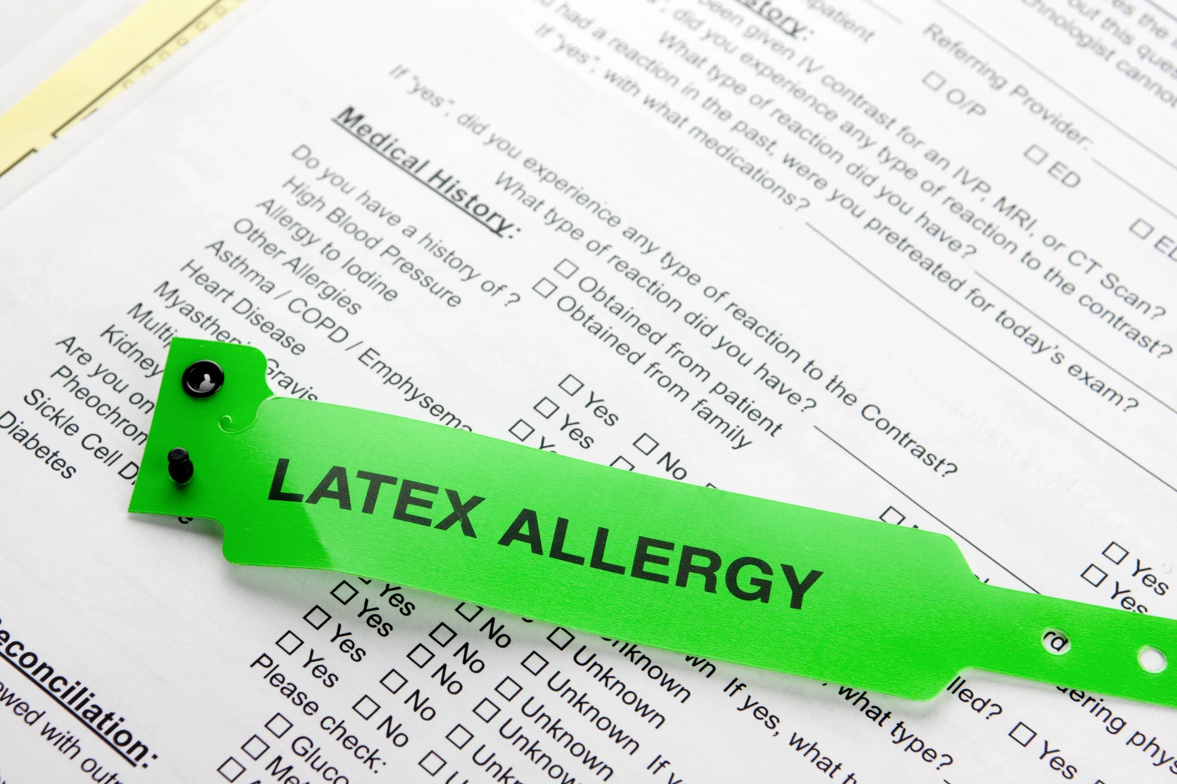 Green latex allergy alert wristband on top of medical history allergy form