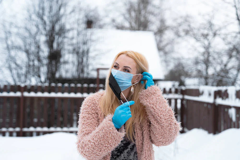 Woman with blue gloves and face mask outside in snowy winter setting