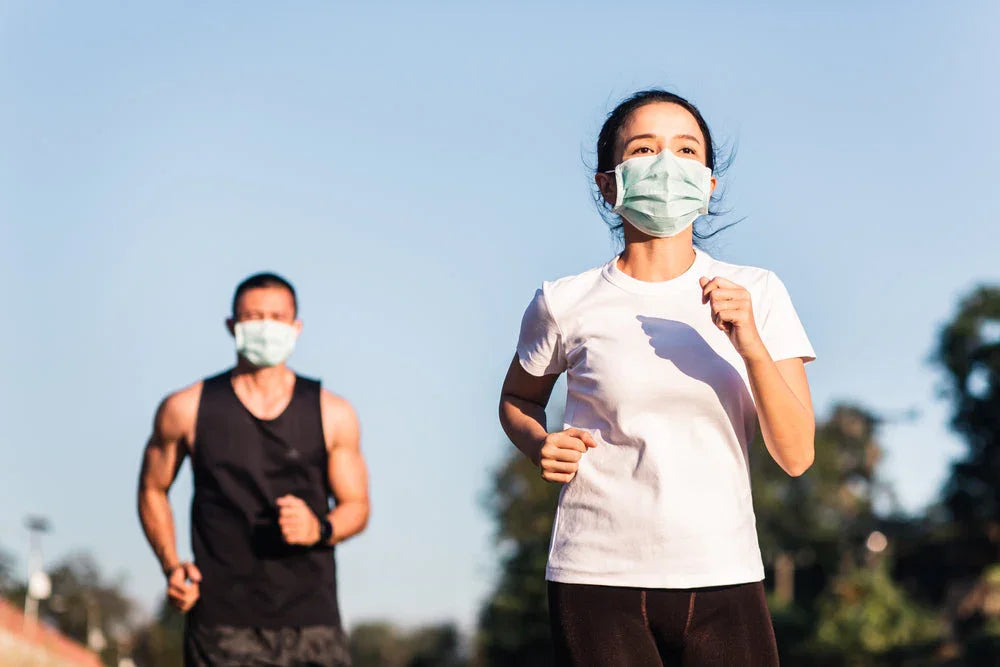 Man and woman jogging outdoors wearing face masks, woman in white hypoallergenic shirt