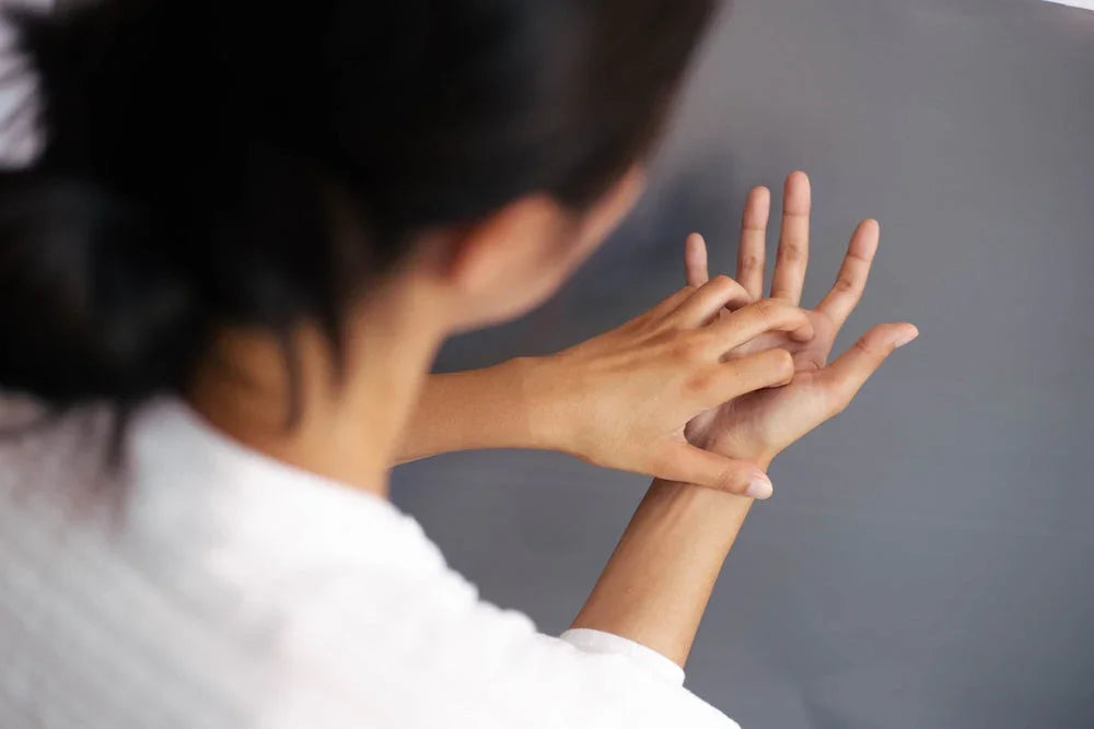 Woman scratching hand, showing eczema or sensitive skin symptoms