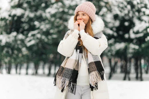 Woman in winter clothing with a knit hat and scarf, standing outdoors in snowy forest