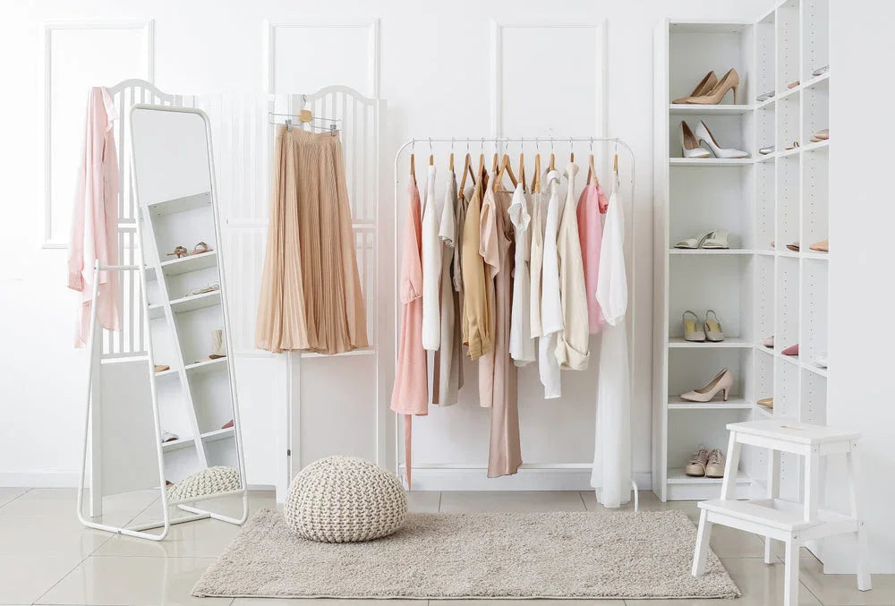 Minimalist closet with neutral cotton clothing, organized shoes, mirror, and cozy decor