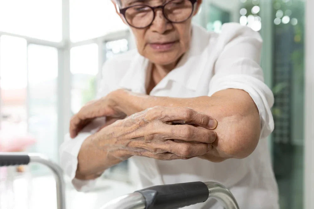 Senior woman with sensitive skin scratching her arm, showing eczema discomfort indoors