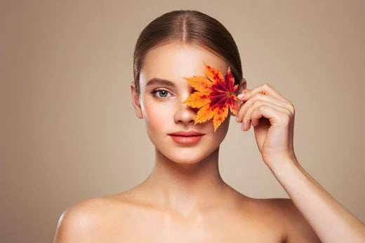 Woman with clear skin holding autumn leaf near eye, representing hypoallergenic apparel