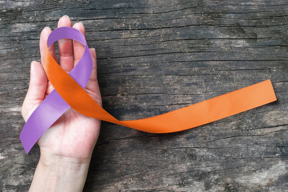 Hand holding purple and orange awareness ribbon on wooden background, allergy-free support