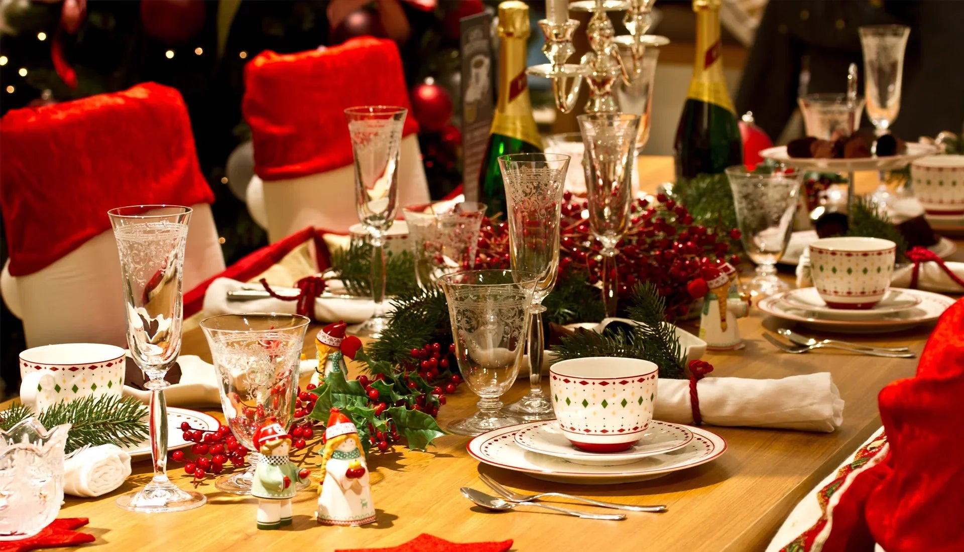 Festive Christmas dinner table with red and green decor, glassware, and holiday-themed china