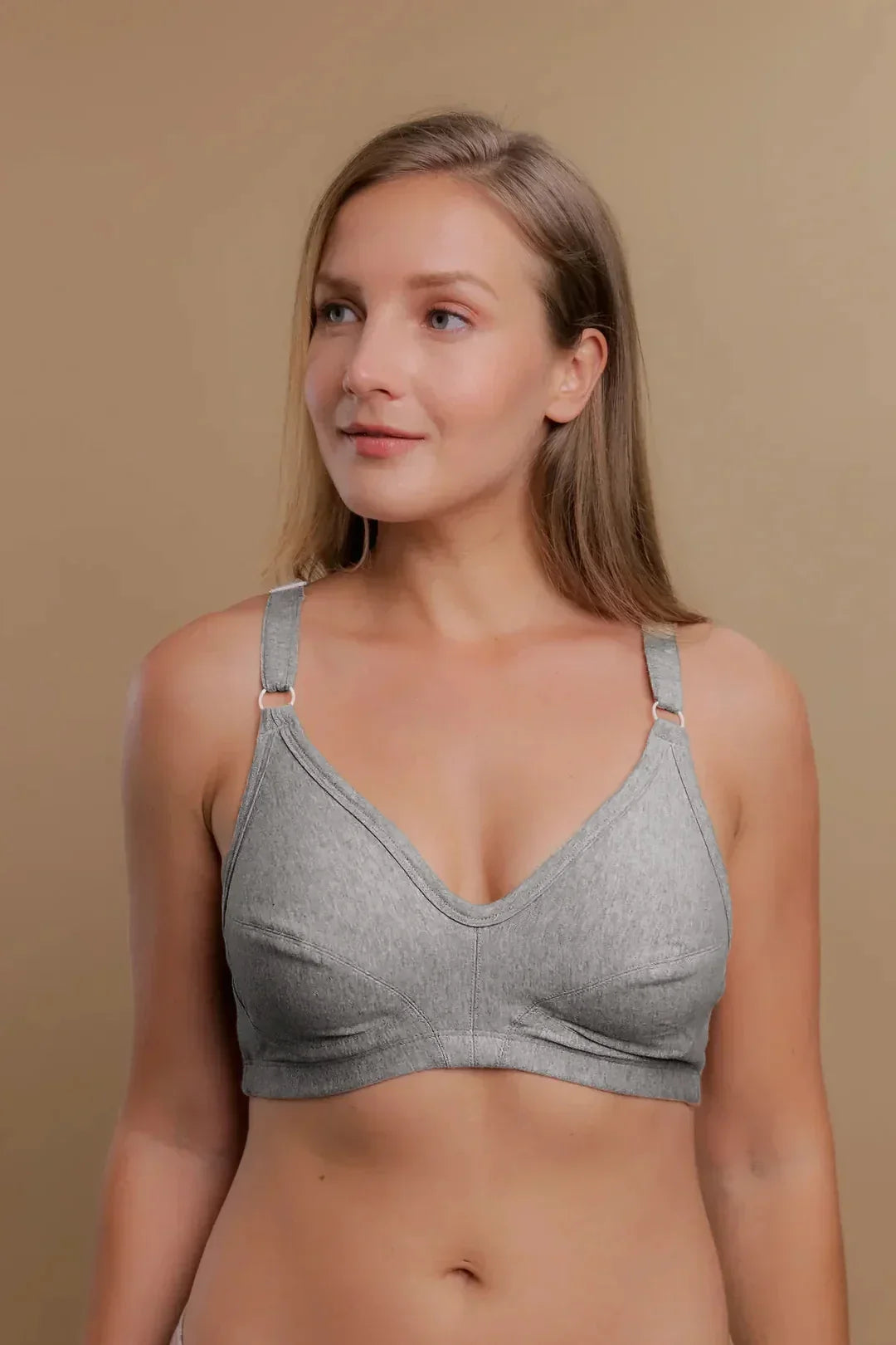 Woman wearing a light grey organic cotton wireless bra for sensitive skin against neutral background